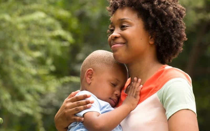 Black mother holding her baby boy to her chest