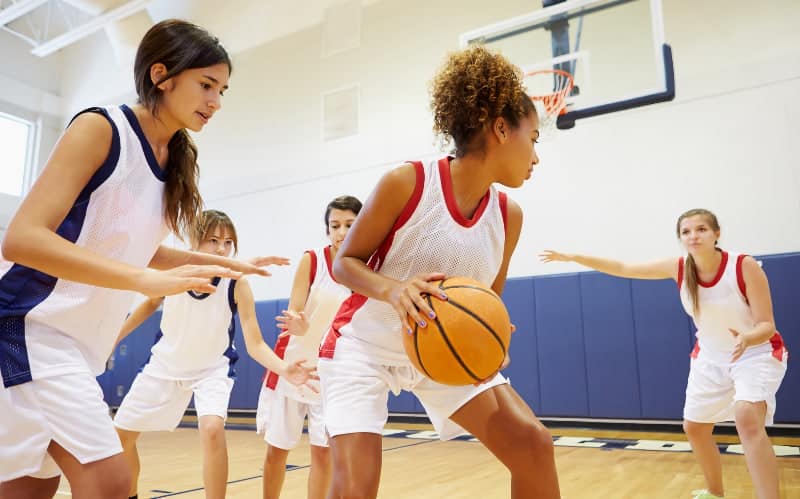 Teen girls playing basketball on an indoor court