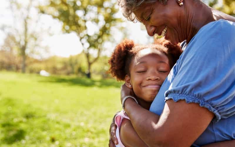 Black woman hugs her smiling granddaughter