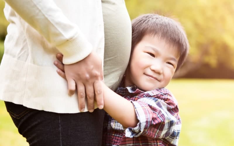 A small boy hugs his pregnant mother