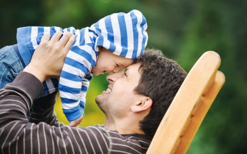 A smiling father plays with his baby